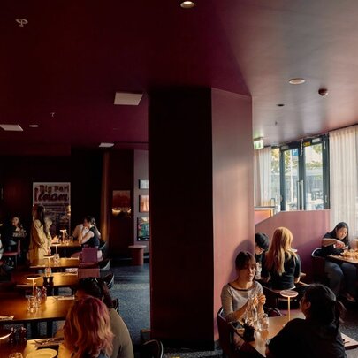Diners at tables in moodily lit restaurant.