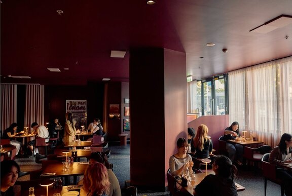 Diners at tables in moodily lit restaurant.