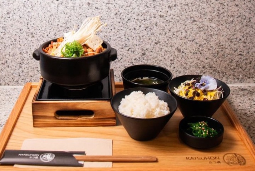 A Japanese meal on a wooden tray with multiple bowls. 