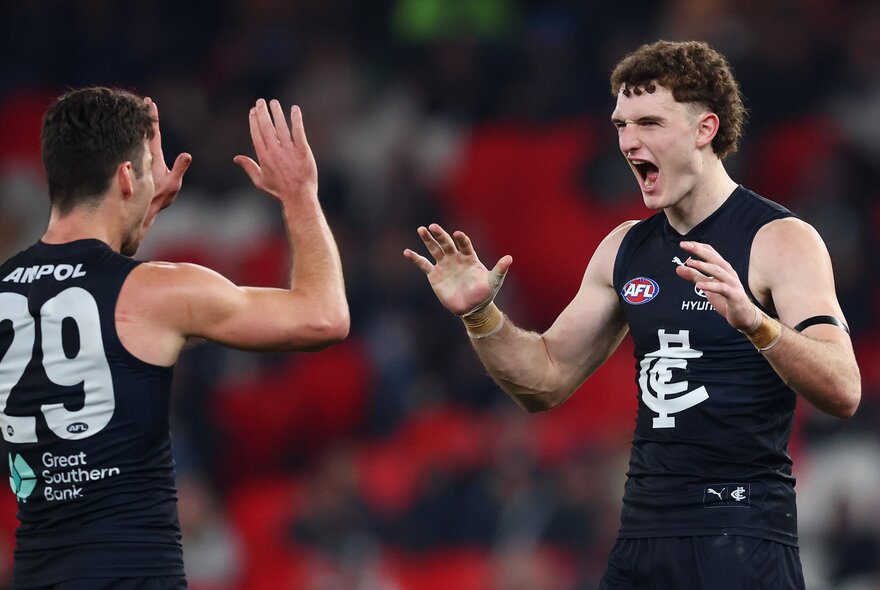 Two Carlton players celebrate after a goal.