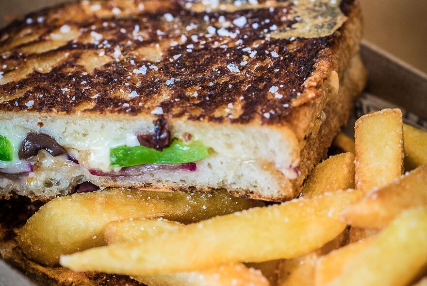 Close-up of a cut toasted sandwich and fries.