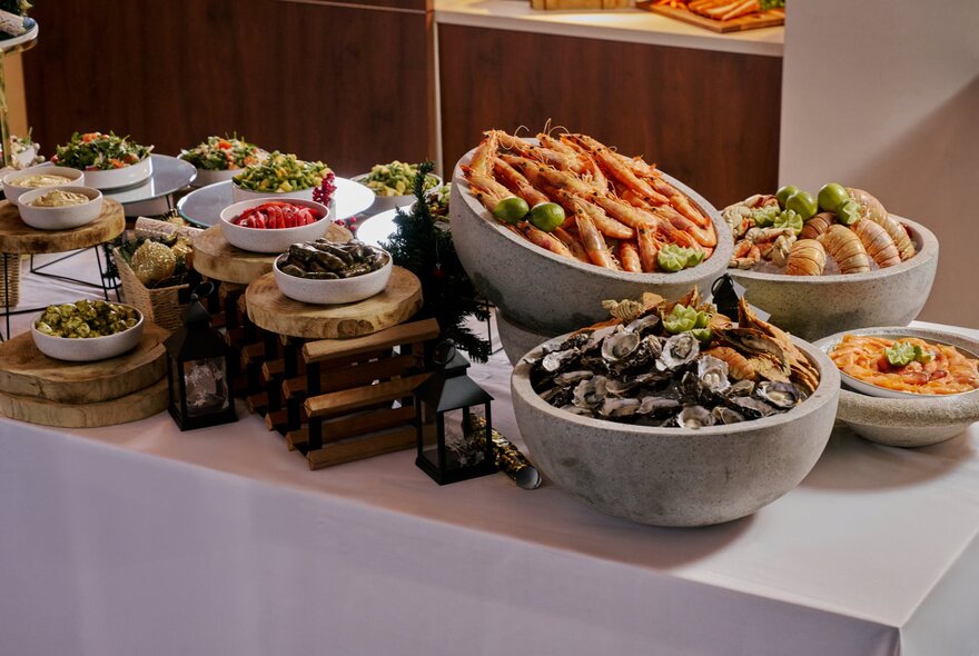 A restaurant buffet with platters of different food including seafood and salads, arranged on a table covered in white linen.