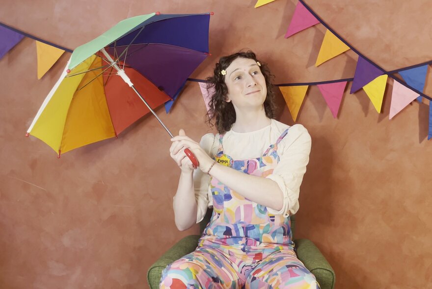 Children's entertainer holding an umbrella under bunting.