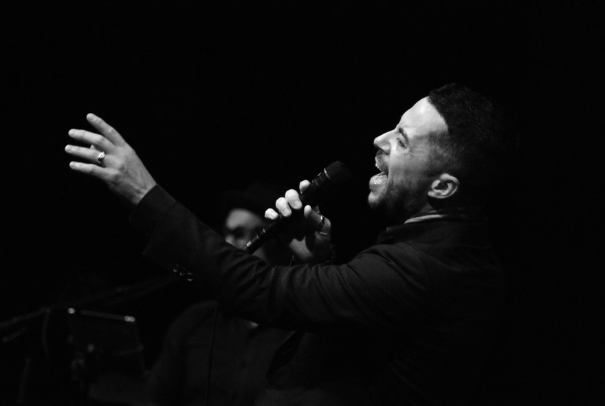 A black and white photo of a singer with his hand outstretched.