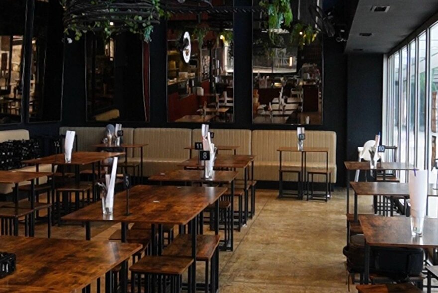 Dark dining space with wooden shared tables and benches.
