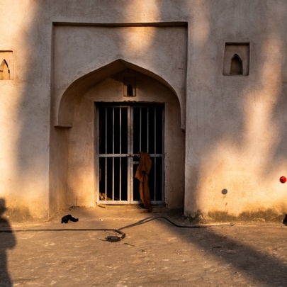Photograph of a doorway in India with two distinct shadows of people. 