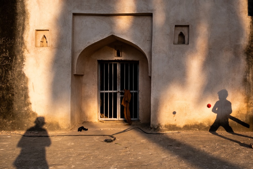 Photograph of a doorway in India with two distinct shadows of people. 