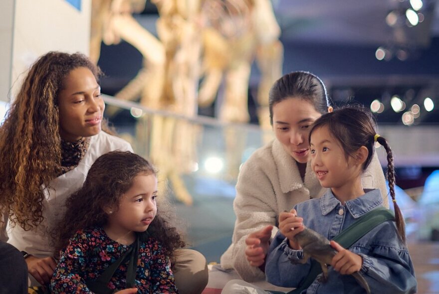 Two young children and two adults inside Melbourne Museum interacting and looking at an object.