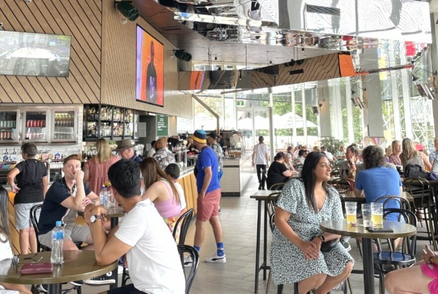 Patrons at a restaurant with wall-to-wall windows during the day.