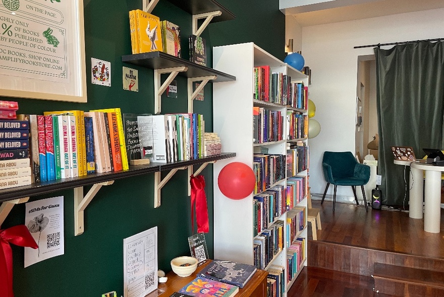 Bookstore with shelves of books and furniture against a green wall.