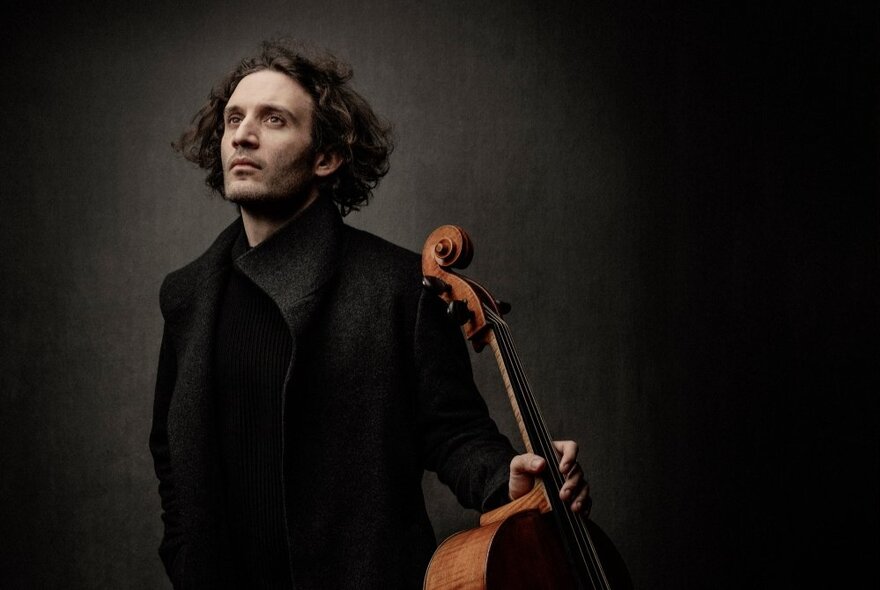 Cellist in a moody setting with his instrument.