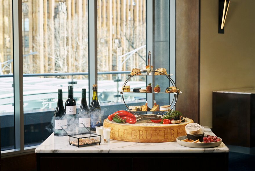 Cheese and wine display on a table near a window.