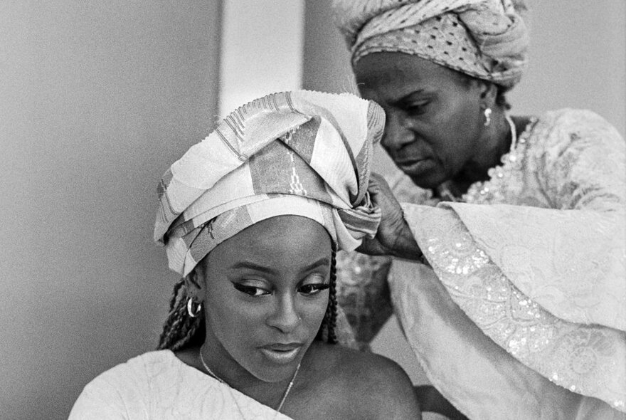 Photojournalism image of two African women arranging their headdresses.