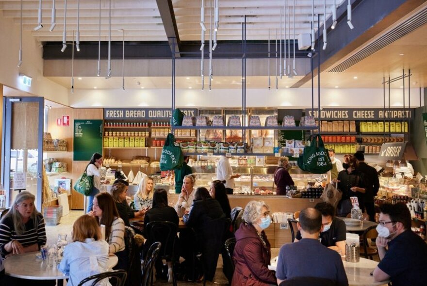 A busy deli restaurant with products lining the walls behind the counter.