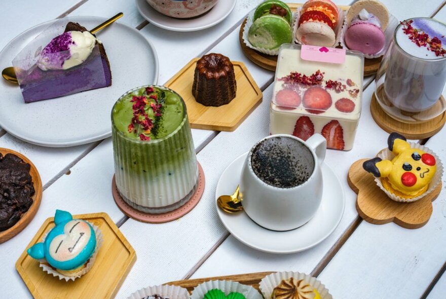 White table filled with colourful cupcakes with fruit and drinks. 