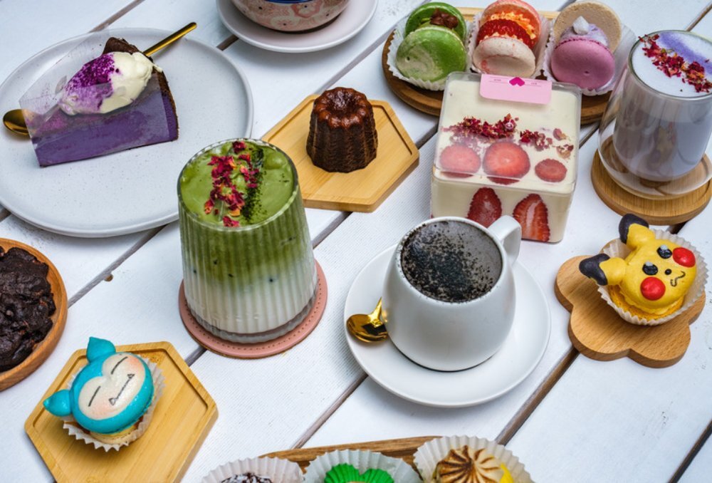 White table filled with colourful cupcakes with fruit and drinks. 