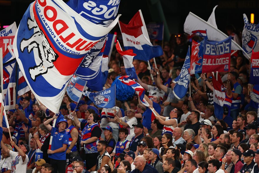 Western Bulldog AFL football fans waving flags and banners in the football stadium during a match.