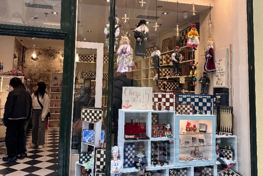 Shopfront in Royal Arcade with displays of Eastern European items including puppets and chess sets.