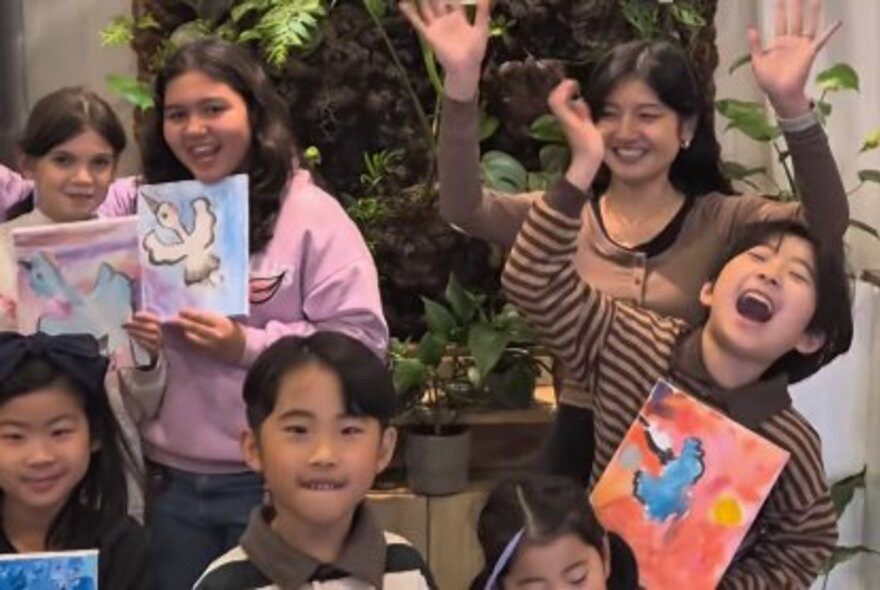 A group of kids holding up pictures and looking happy in a class situation. 