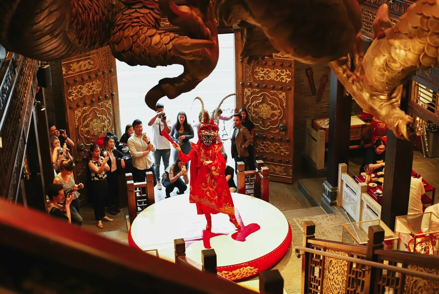 People watching a traditional Chinese dance performance inside a Chinese restaurant.