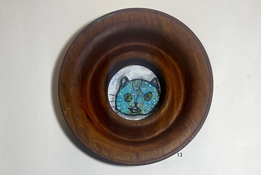 Drawing of a blue cat in a round wooden frame.