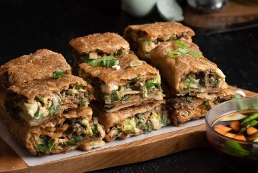 Sliced squares of Indonesian martabak, a dense pancake filled pancake, piled up on a plate.