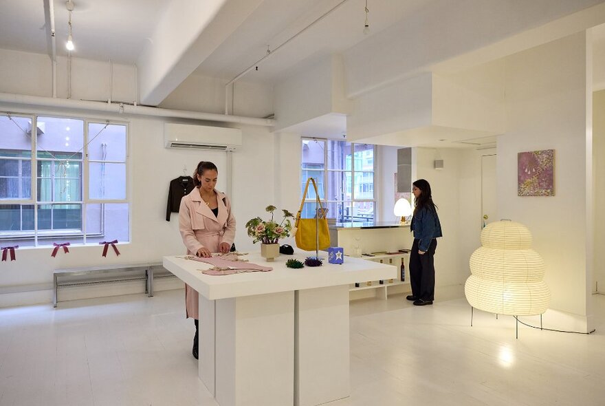 Two women browsing in an aesthetic boutique with a large paper floor lamp.
