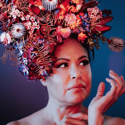 Torres Strait Islander singer-songwriter Christine Anu, wearing a red-toned floral headdress.