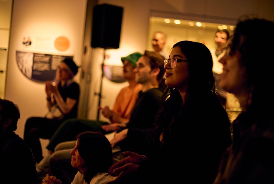 A group of people in an indoor setting listening to a presentation or performance, part of Nocturnal, Melbourne Museum at night.