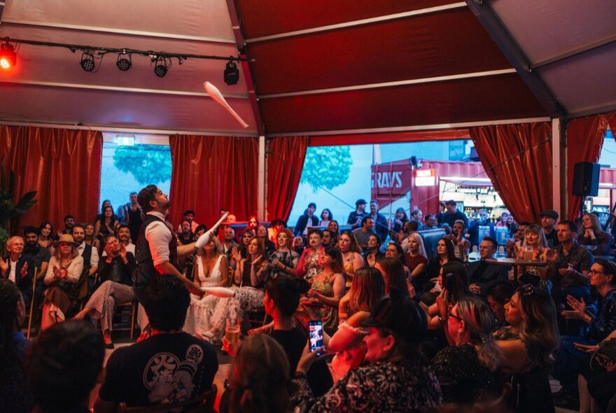 The circular interior of the Spiegel Haus, with audiences watching a juggler peform.