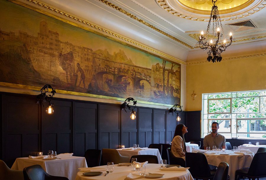 A couple dining under a mural in a fine dining restaurant.