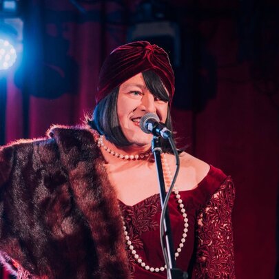Cabaret performer Tina Del Twist on stage wearing a fur stole.