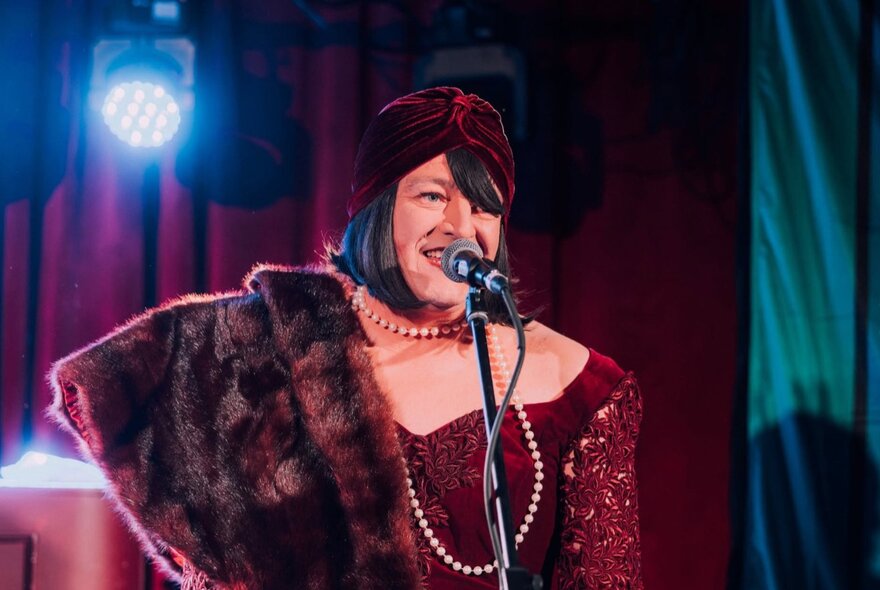 Cabaret performer Tina Del Twist on stage wearing a fur stole.