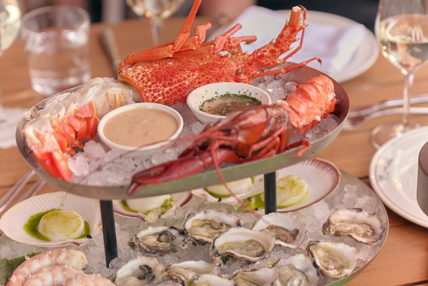 A two-tiered platter with shelled prawns and oysters on the bottom, and lobster and a Moreton Bay bug on the top.