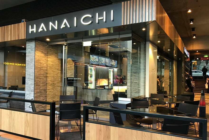 Cafe exterior with signage, wooden details, black tables and chairs.