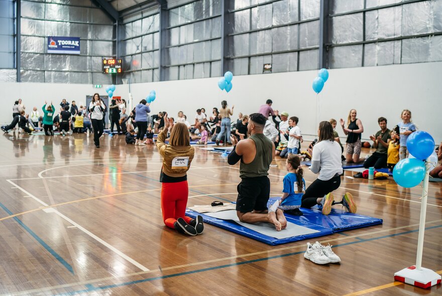 The Melbourne Great Sarcoma Plank-A-Thon  event, inside a large indoor hall, with people kneeling on exercise mats.