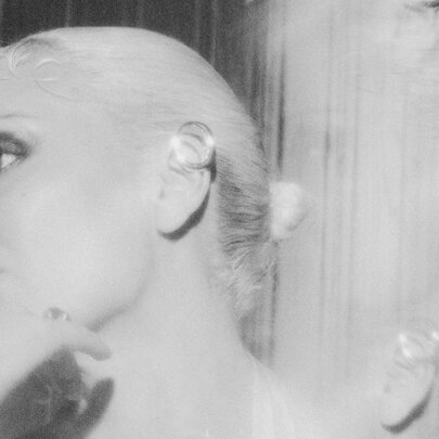 Artist George Maple in profile, her head leaning back on a wall; black and white.