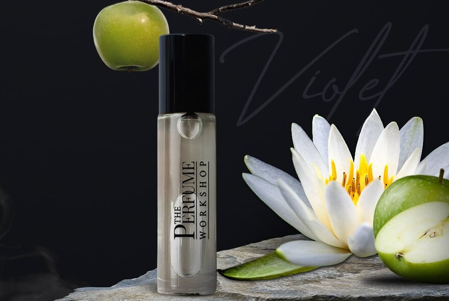 A perfume bottle next to a lotus and green apple.