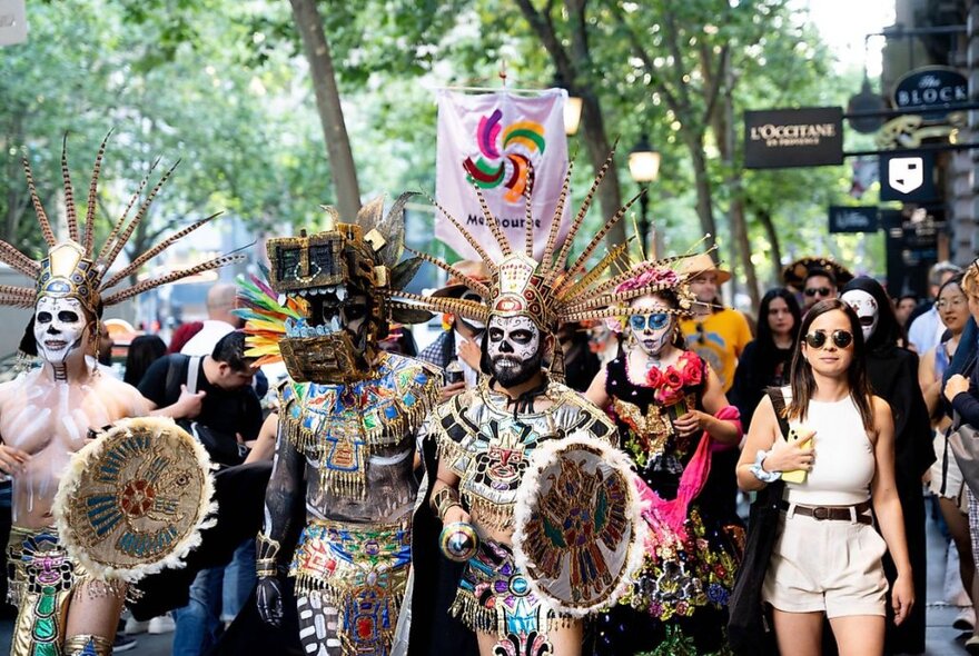 People participating in a Mexican Day of the Dead Catrina Walk, some wearing elaborate costumes and others in normal clothing.