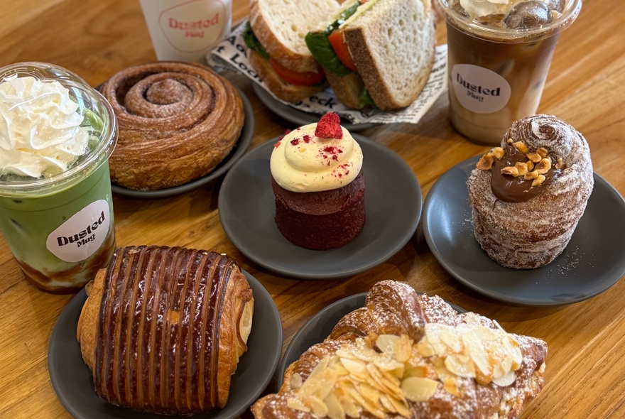 Selection of muffins, pastries, sandwiches and matcha latte.