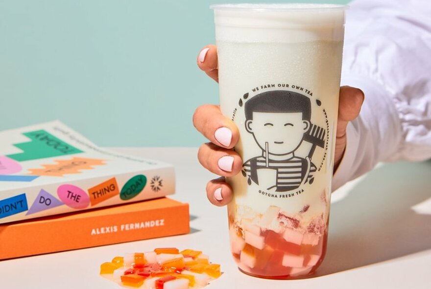 A woman's hand holding a plastic container of bubble tea