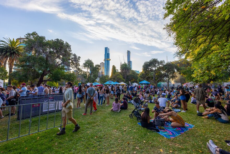 Crowds milling around a festival in a city park.