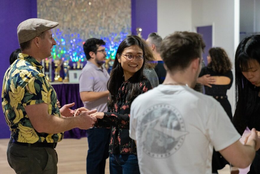 Groups of people holding hands during a dance lesson.