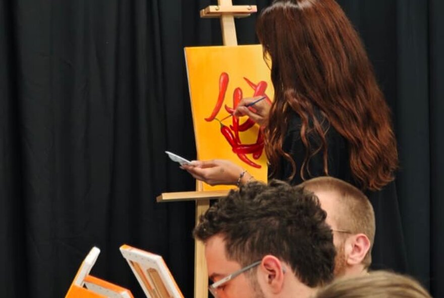 Workshop participants painting on small canvases.