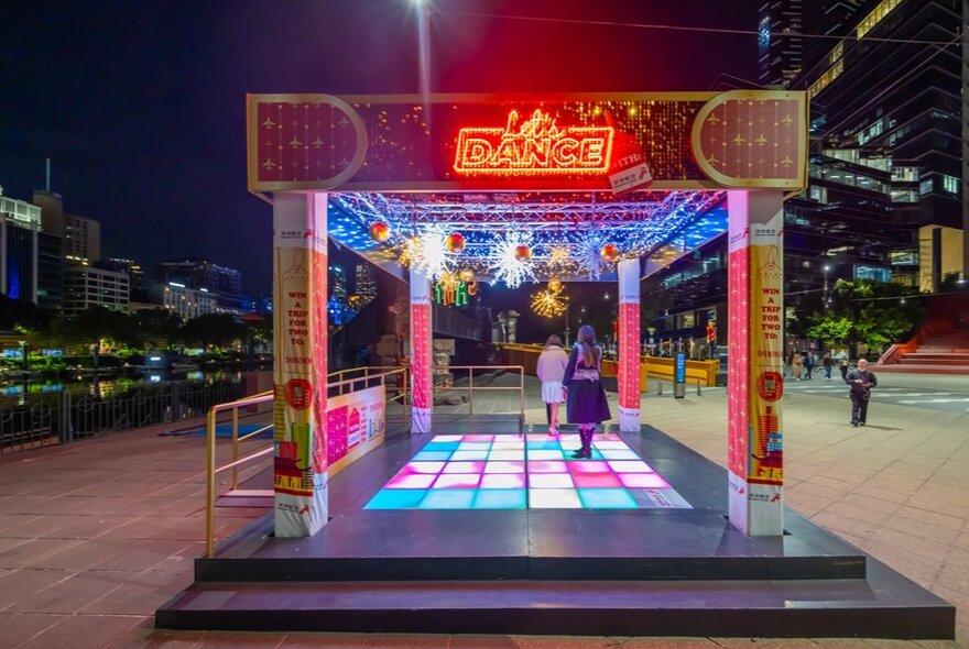 A light up dance floor under glowing Christmas decorations. 