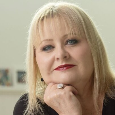 Author and podcaster Vikki Petraitis, with straight blonde hair, resting her chin on her hand.