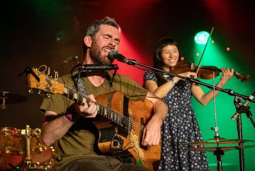 Folk musicians performing - a male singer / guitarist and a female violinist.