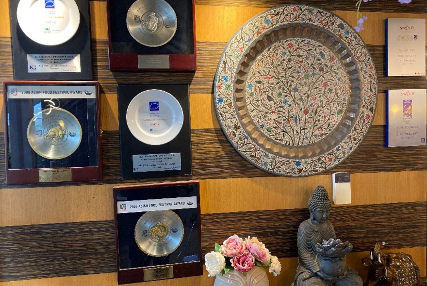 A striped wall with decorative plates and awards hung on it.