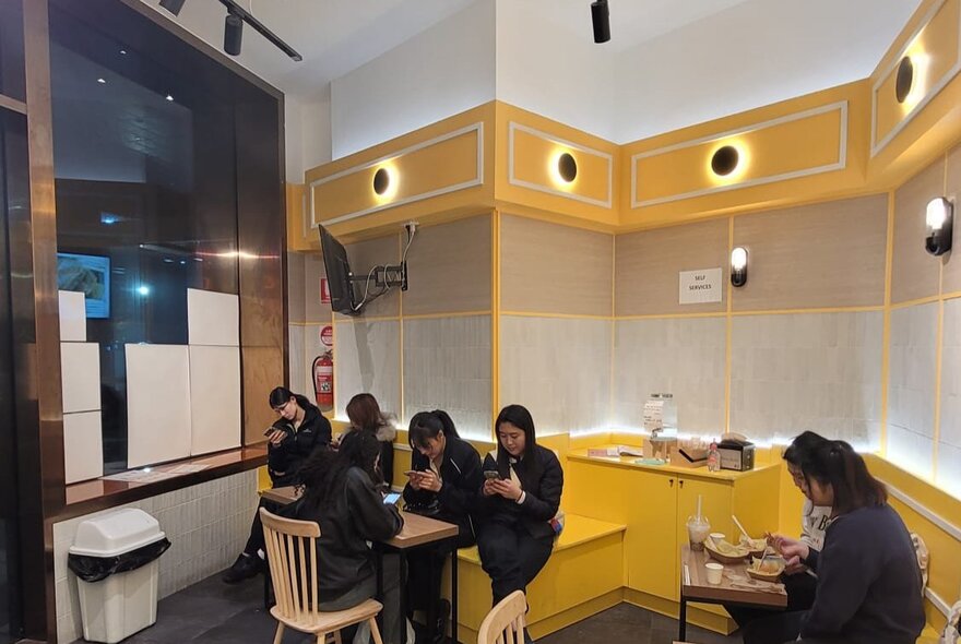 The yellow interior of a Hong Kong-style cafe with seated patrons.