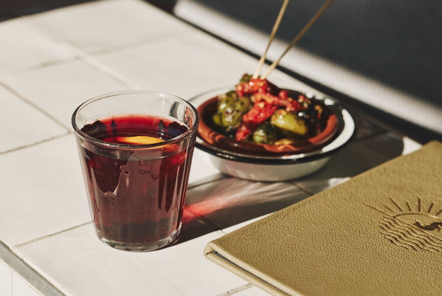 A glass of mulled wine next to a tapas plate and menu.